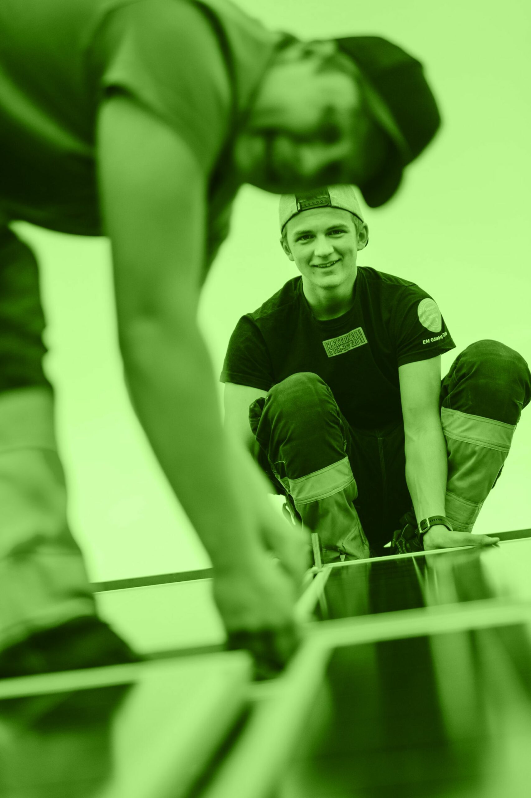 Två glada män som monterar solceller på en fastighet